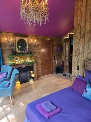a bedroom with a purple ceiling with a bed and a chandelier at Cabane d'Oniria in Palaja