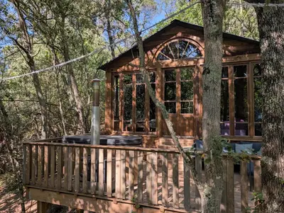 a cabin in the woods with a large deck at Cabane d'Oniria in Palaja
