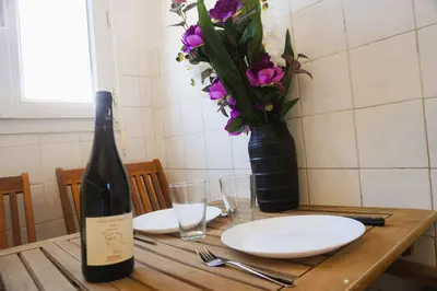 a bottle of wine and a vase with flowers on a table at L'anguille du port clim jardin mer in Port-la-Nouvelle