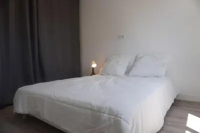 a bed with white sheets and pillows in a bedroom at Le Dauphin du port in Port-la-Nouvelle