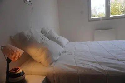 a bedroom with a white bed with a window at Le Dauphin du port in Port-la-Nouvelle