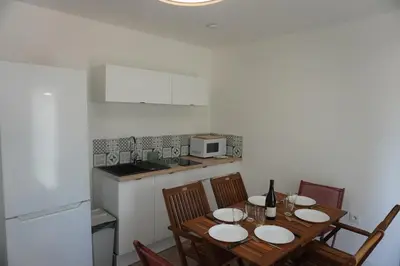 a kitchen with a wooden table with chairs and a microwave at Le Dauphin du port in Port-la-Nouvelle