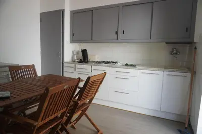 a kitchen with white cabinets and a wooden table and chairs at L'espadon du port, air conditioning, terrace, sea, 5 people in Port-la-Nouvelle