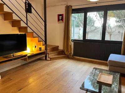 a living room with a television and a staircase at Artistic house in Carcassonne