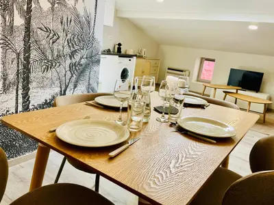 a wooden table with plates and wine glasses on it at L'escale cocoon - cozy and relaxing in Villefranche-de-Lauragais