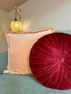 a red pillow sitting next to a pillow with a lamp at L'escale cocoon - cozy and relaxing in Villefranche-de-Lauragais