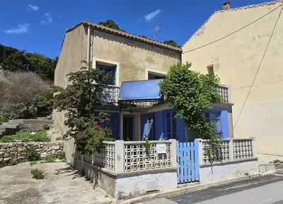 a house with a blue door and a white fence at Maison bleu avec vue mer, étang & Pyrénées in Bages