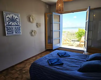 a bedroom with a blue bed and a large window at Maison bleu avec vue mer, étang & Pyrénées in Bages