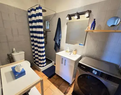 a small bathroom with a sink and a washing machine at Maison bleu avec vue mer, étang & Pyrénées in Bages