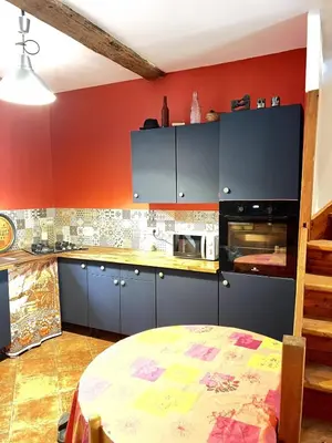 a kitchen with blue cabinets and a red wall at Maison de village pleine de charme, 7 couchages in Vingrau