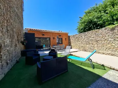 a patio with furniture and a stone wall at L'Enclos de Nathalie et Jacques in Rieux-Minervois