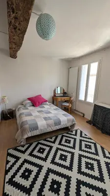 a bedroom with a bed with a black and white rug at Le Nid de Marguerite in Castelnaudary