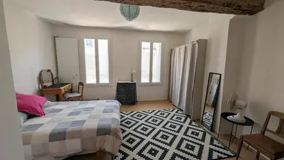 a bedroom with a bed and a desk and windows at Le Nid de Marguerite in Castelnaudary