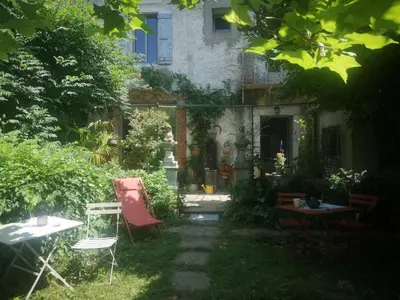 a garden with chairs and tables in front of a house at Une chambre au jardin in Saint-Pons-de-Thomières