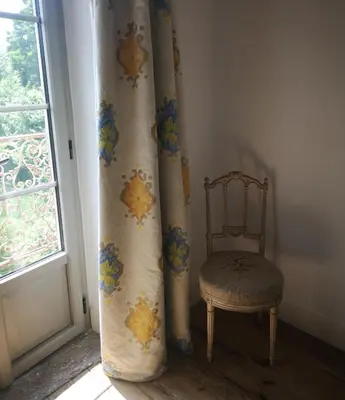 a chair and curtain in a room with a window at Une chambre au jardin in Saint-Pons-de-Thomières