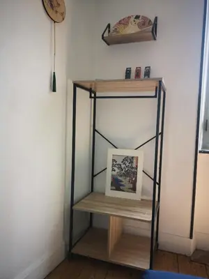 a shelf in the corner of a room with a picture at Une chambre au jardin in Saint-Pons-de-Thomières