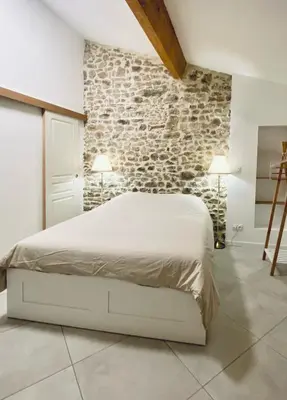 a bedroom with a white bed and a stone wall at Le Bastion, 15 guests, 5 suites, 5 baths, AC in Pouzols-Minervois