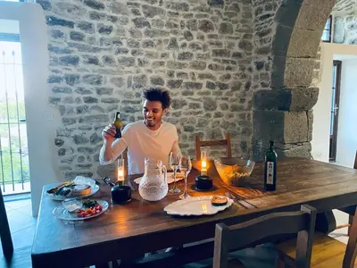 a man sitting at a table with a bottle of wine at Le Bastion, 15 guests, 5 suites, 5 baths, AC in Pouzols-Minervois