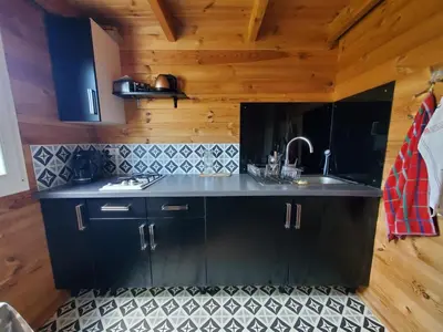 a kitchen with black cabinets and a sink at Le Chalet du Grain d'Orient in Caudiès-de-Fenouillèdes