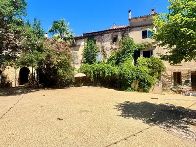 an old house with a large courtyard in front of it at La Maison du Rond in Coustouge