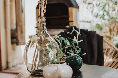 a table with a glass bottle and two vases on it at Gîte - Holiday Home Vent Cers in Limoux