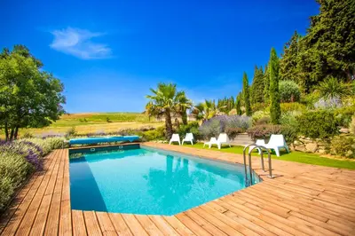a swimming pool with two white chairs and a wooden deck at Gîte - Holiday Home Vent Cers in Limoux