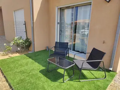 two chairs and a table on a lawn in front of a house at Studio cosy proche des vignes in Roubia