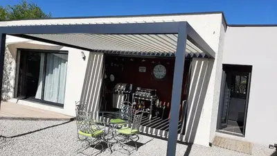 a pavilion with chairs and a clock on a building at Havre de paix avec piscine et jacuzzi Narbonne in Ventenac en Minervois