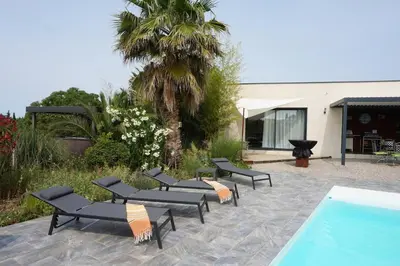 a group of black lounge chairs next to a swimming pool at Havre de paix avec piscine et jacuzzi Narbonne in Ventenac en Minervois