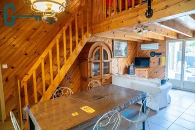 a kitchen and living room with a wooden ceiling at Séjour détente avec spa, piscine et sauna in Mas-Saintes-Puelles