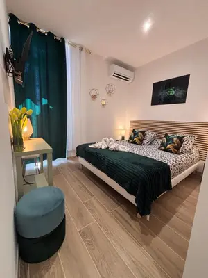 a bedroom with a bed and a green curtain at L'Emeraude in Narbonne