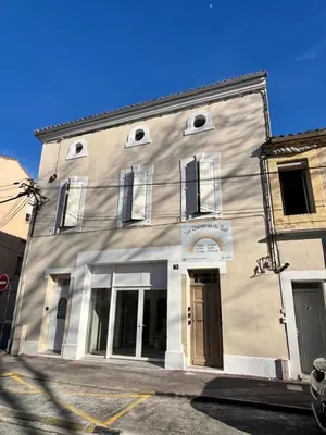 a gray building with windows on a street at L'Emeraude in Narbonne