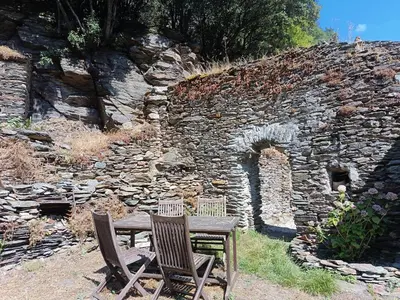two chairs and a wooden table in front of a stone wall at Chambre et b&b in Miraval-Cabardès