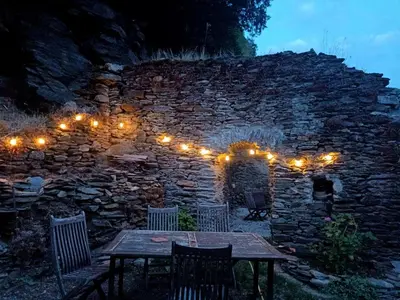 a stone wall with a wooden table and lights at Chambre b&b in Miraval-Cabardès