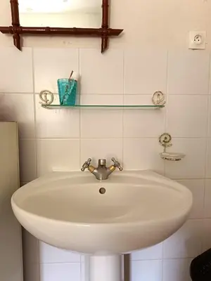 a white sink in a white tiled bathroom at Chambre b&b in Miraval-Cabardès