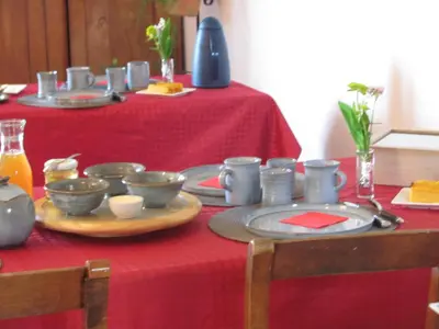 a table with a red table cloth with dishes on it at Au pied du Figuier in Pauligne