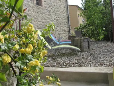 a garden with a chair and a table and flowers at Au pied du Figuier in Pauligne