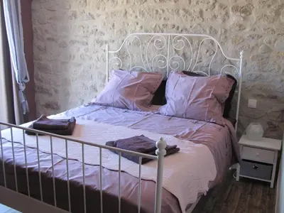 a bedroom with a white bed with purple sheets and pillows at Au pied du Figuier in Pauligne