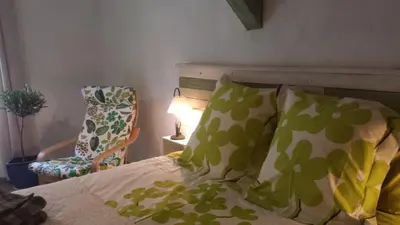 a bed with green and white pillows and a chair at Au pied du Figuier in Pauligne