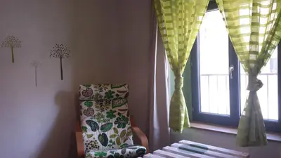 a room with a chair and a window with curtains at Au pied du Figuier in Pauligne