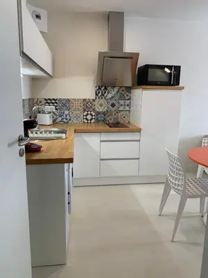 a kitchen with white cabinets and a table and chairs at Gili Air, Les Halles et les Grands Buffets in Narbonne