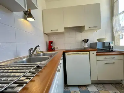 a kitchen with white cabinets and a sink at L'appartement des boulangers in Carcassonne