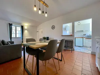 a dining room and living room with a table and chairs at L'appartement des boulangers in Carcassonne