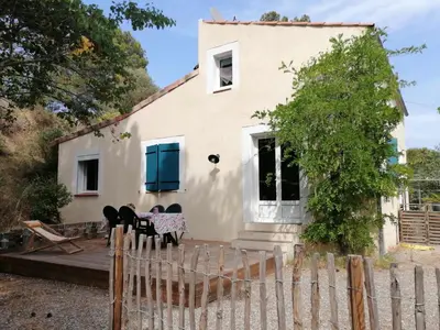 a white house with blue shutters and a fence at Maison dans les Corbières in Montséret