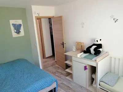 a bedroom with a bed and a stuffed panda bear sitting on a desk at Maison dans les Corbières in Montséret