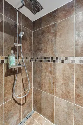a bathroom with a shower with brown tiles at La Porte de la Cité, Maison Historique Vue Château in Carcassonne
