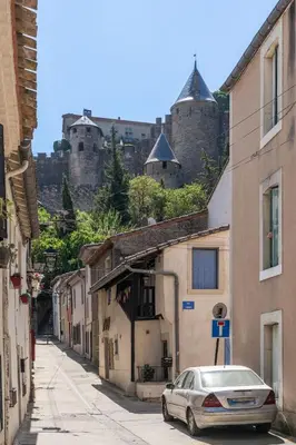 a car parked in a street with a castle in the background at La Porte de la Cité, Maison Historique Vue Château in Carcassonne