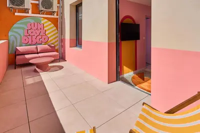 a waiting room with a pink couch and a tv at La Villa Orange - DISCO - proche cité médiévale et centre ville à pied in Carcassonne