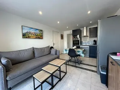 a living room with a couch and a kitchen at Le Montille - Appartement face au Port - Climatisation et Wifi in Port-la-Nouvelle