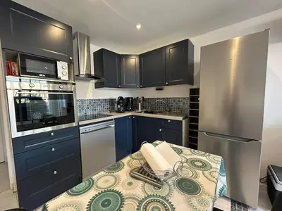 a kitchen with blue cabinets and a table with a counter top at Le Montille - Appartement face au Port - Climatisation et Wifi in Port-la-Nouvelle
